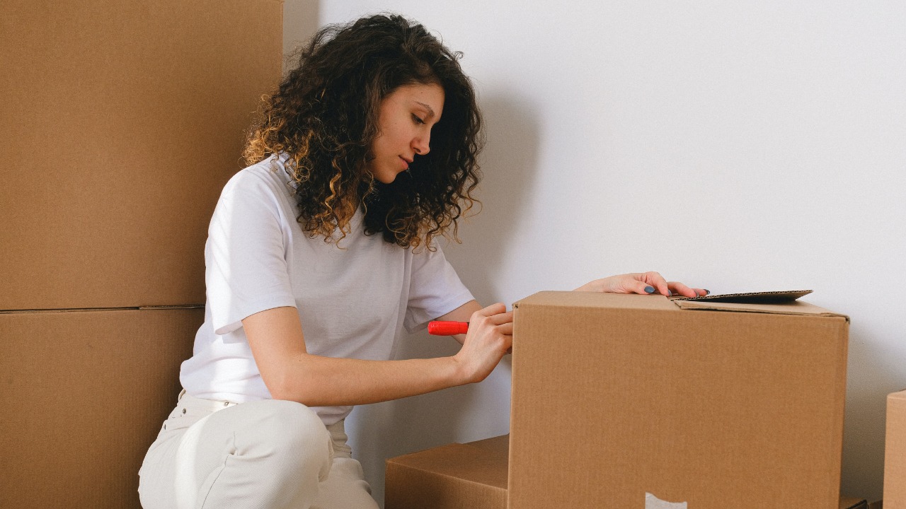 A woman labels a box while packing up her home during a move