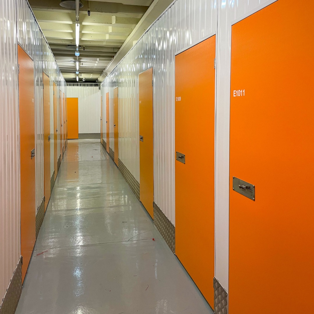 A corridor of a storage facility with several storage units side-by-side.