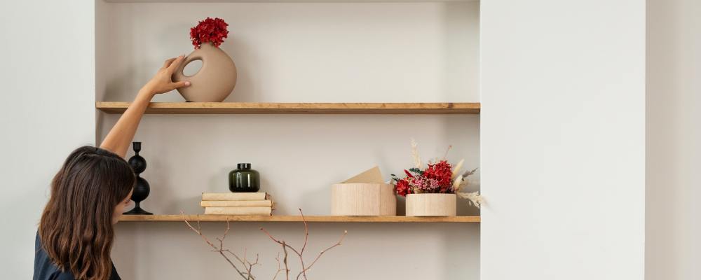 A happy homeowner storing away items on a floating shelf in their small home